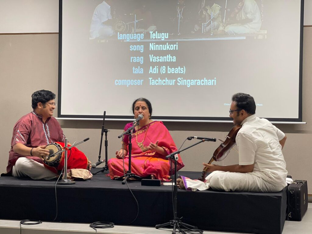 A classic Indian music band sitting on a stage performing with voice and instruments