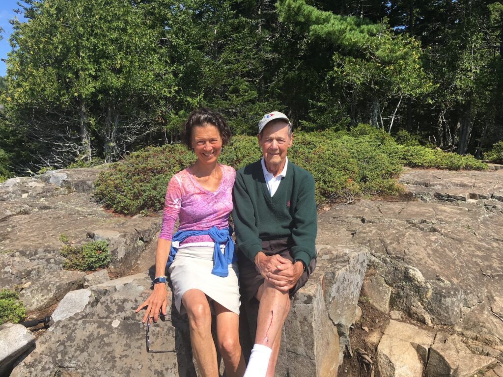 Susan Carlson sitting on a rock with her father Sam Lawrence during a hike.