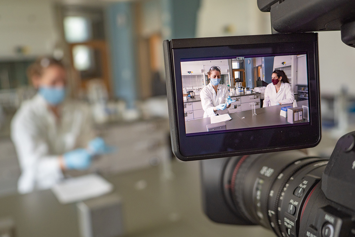 Camera set up to film two masked lecturers in a chemistry lab
